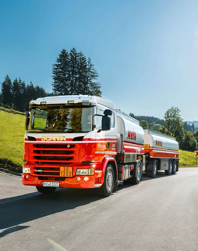 Ciężarówka Scania typu komercyjnego z zderzakiem pokrytym smołą. Ten pojazd użyteczności publicznej posiada system kół samochodowych i opony.