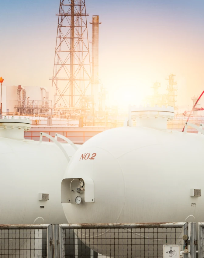 Zbiornik magazynowy, rury i cylindry w fabrycznym otoczeniu przemysłowym. Znaczone pojemniki obejmują zbiorniki paliwa i silosy.